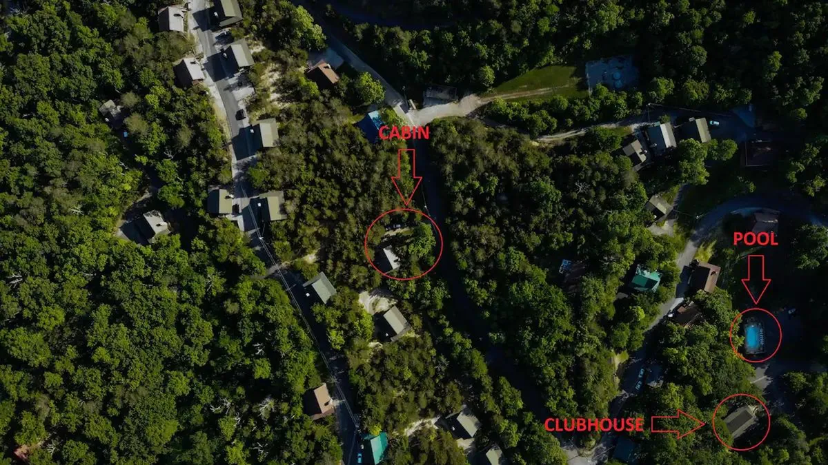 An inviting exterior shot featuring a cabin with a pool and clubhouse in the background. The pool area is nestled in nature, offering a space for swimming, relaxing, and socializing after a day of outdoor pursuits.